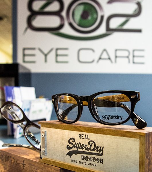 SuperDry brand glasses on display with 802 Eye Care logo in the background